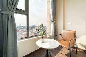 Una stanza con vista sulla città attraverso una finestra, un tavolo con una pianta in vaso e una poltrona in pelle.