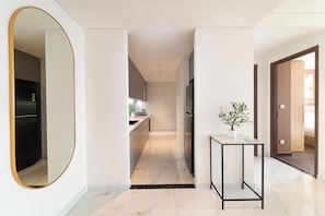 Una cucina moderna con pavimento in marmo, un piccolo tavolo con una pianta e un corridoio che conduce a una camera da letto.