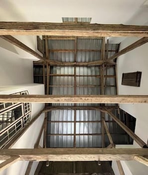 Ein mehrgeschossiges Interieur mit freiliegenden Holzbalken und Fenstern mit Metallrahmen.
