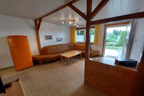 Ein Zimmer mit Holzboden, einer Couch, einem Tisch, einem Fenster und einer Tür.