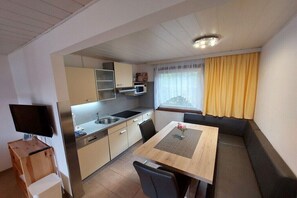 Eine kleine Küche mit Mikrowelle, Spüle und Esstisch aus Holz.