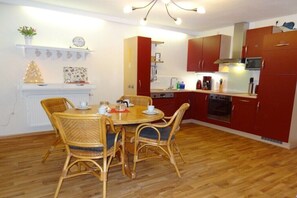 Cocina compacta con armarios rojos, microondas y cafetera.