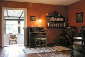 Ein Zimmer mit Holzboden, Bücherregal, Stuhl und Fenster.