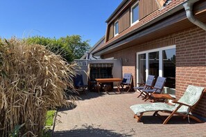 Eine Terrasse mit Gartenmöbeln, einem Tisch und Stühlen.