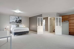 A bedroom with a bed, bedside lamps, a desk, a painting, and a wardrobe. - Pokeno Country Retreat | Spa, BBQ and Rural Views (Pōkeno)