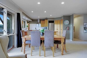 Un coin repas avec une table et des chaises, une cuisine en arrière-plan et une horloge au mur.