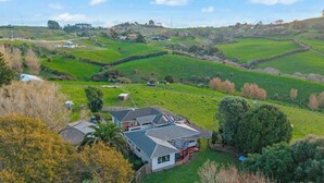 Uma casa com telhado inclinado, rodeada por campos verdes e árvores.