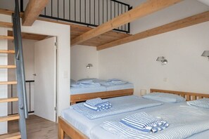 A room with two bunk beds, wooden beams, white walls, and two wall-mounted lamps. - Holiday apartment with 2 bedrooms (Loddin)