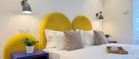 Een keurig opgemaakt slaapkamer met een bed, nachtkastjes en een potplant.