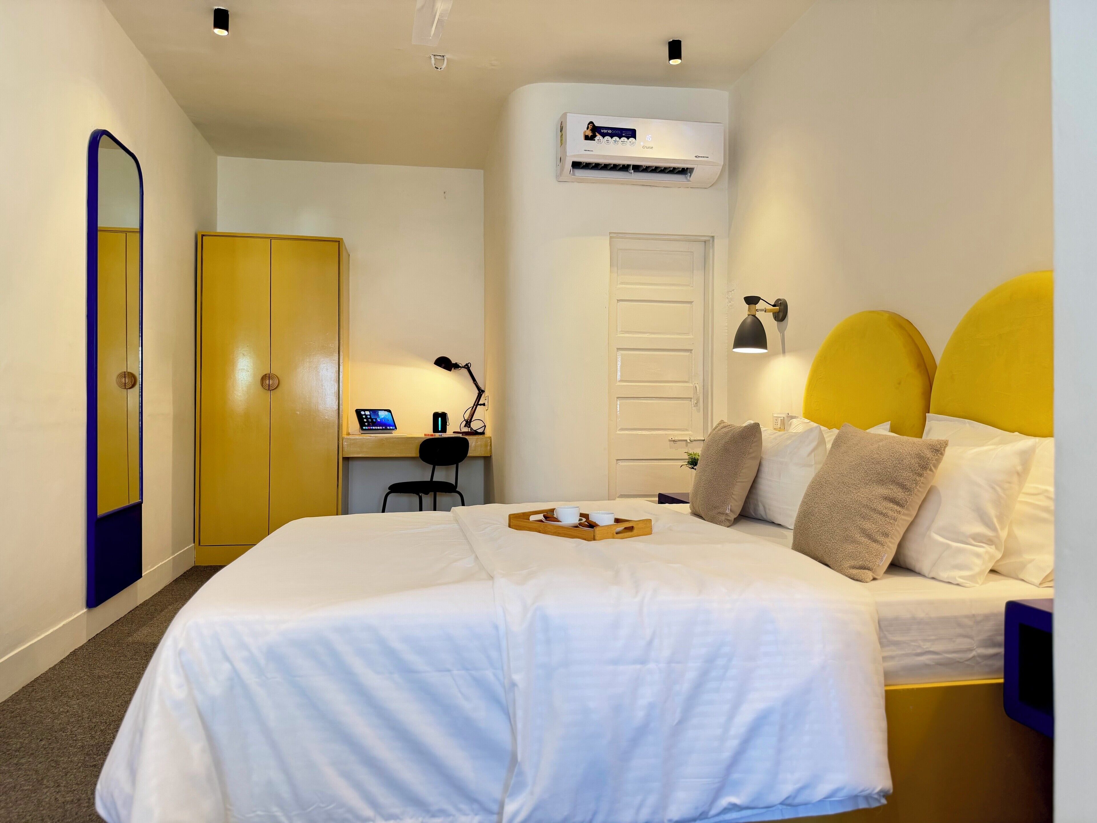 Habitación de hotel con cama, escritorio con computadora, silla, armario y equipo de aire acondicionado.