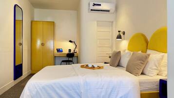 Habitación de hotel con cama, escritorio con computadora, silla, armario y equipo de aire acondicionado.