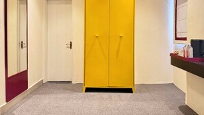 A hallway with a yellow wardrobe, a door, and a small counter with items. - NauKothi Jaipur (Jaipur)