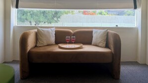 A brown sofa with two pillows and a tray with two glasses of red wine. - NauKothi Jaipur (Jaipur)