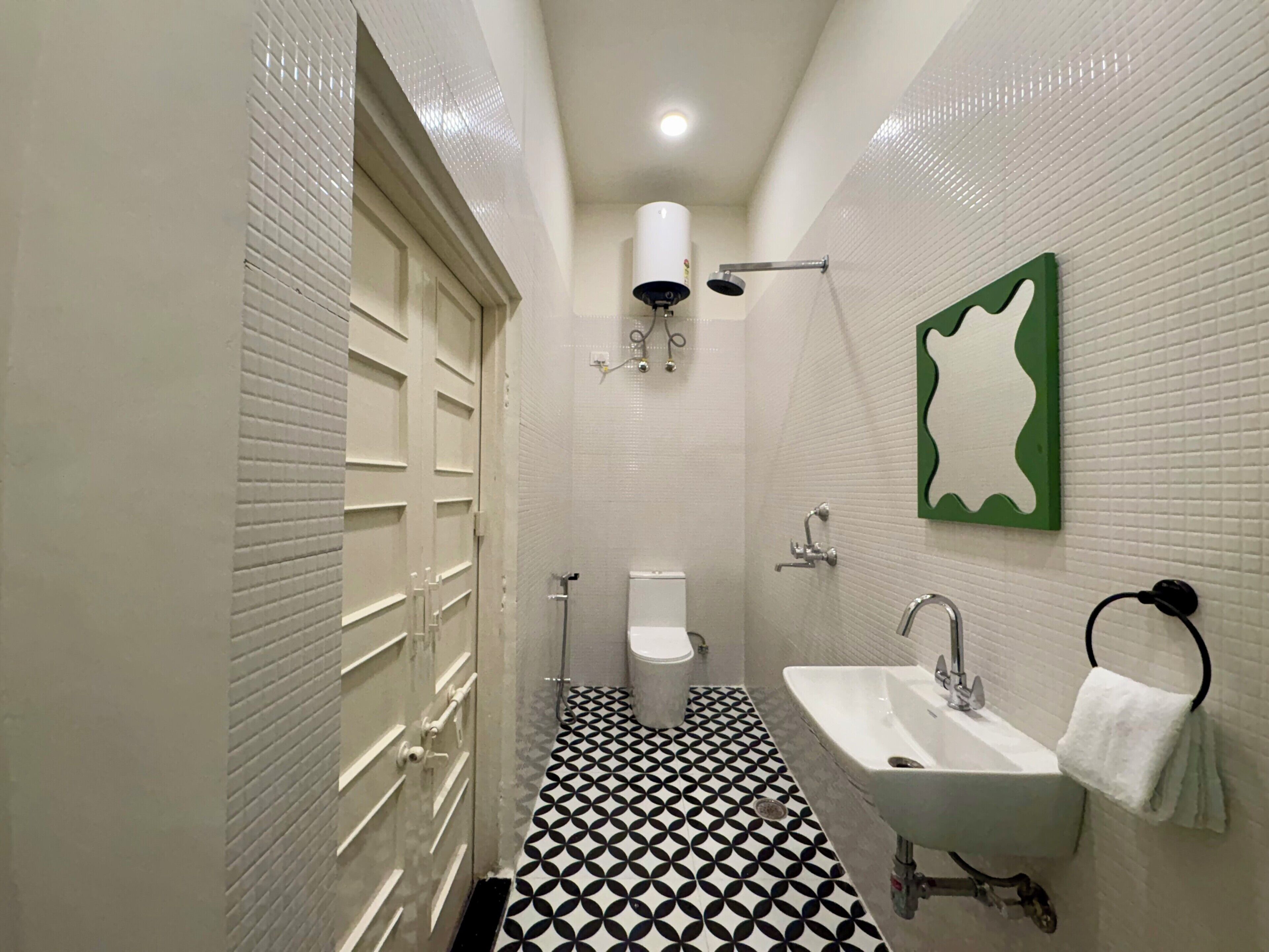 Un baño con piso de baldosas blanco y negro, un lavamanos blanco, un inodoro y una ducha.
