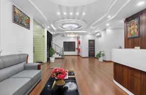 En moderne reception med sofa, et skrankebord, en trappe og et dekorativt loft.
