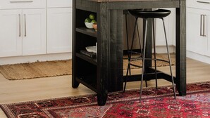Una cucina con mobili bianchi, un'isola in legno, uno specchio rotondo e un forno a microonde.