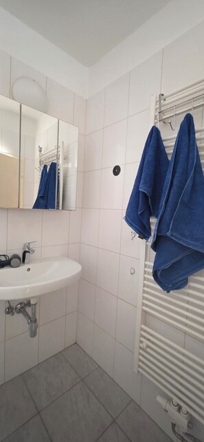 A bathroom with a white sink, a mirror, and a towel rack with blue towels.