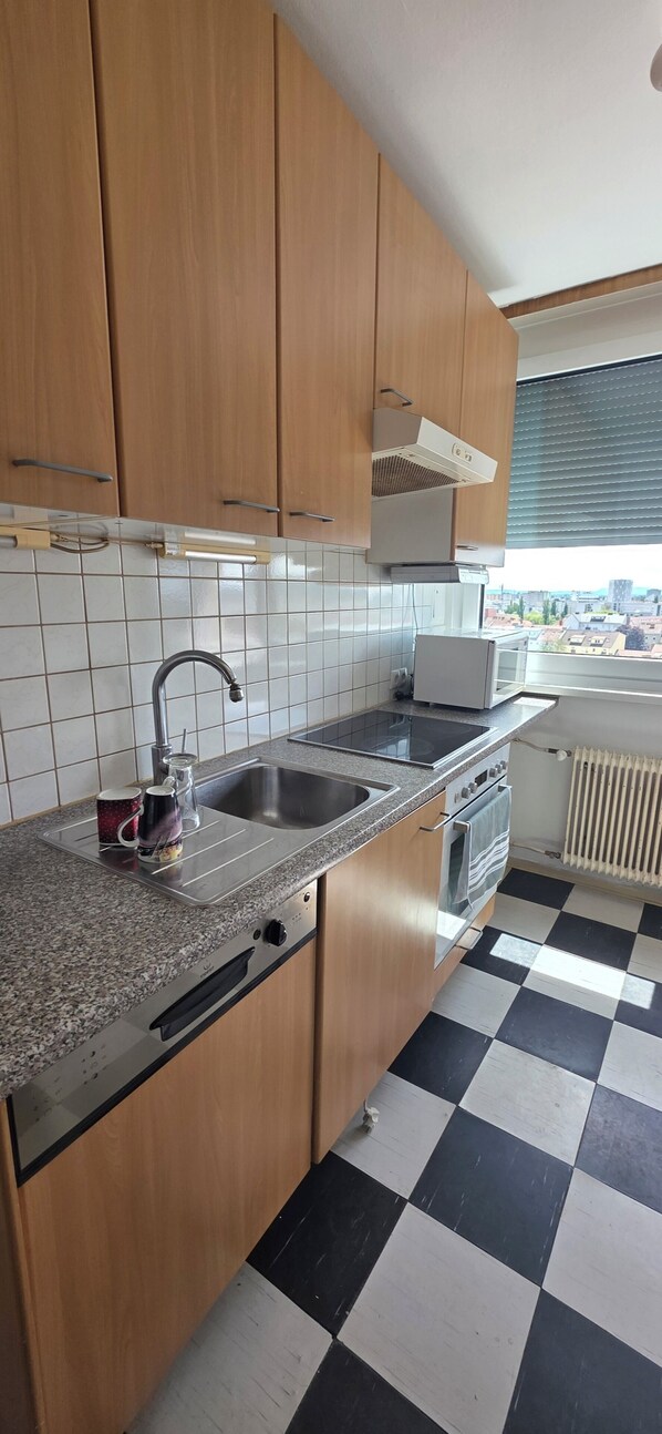 A kitchen with wooden cabinets, a stainless steel sink, a built-in oven, and a checkered floor.