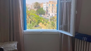 A room with a window, a radiator, and a small table. - Ritza Hotel (Tunis)