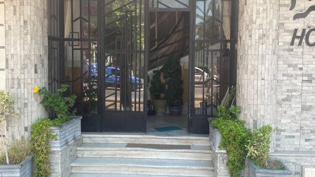 A hotel entrance with a glass door, steps leading up to it, and potted plants on either side. - Ritza Hotel (Tunis)
