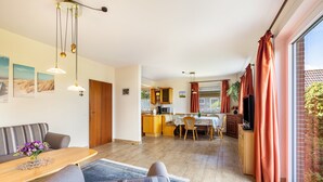 En moderne stue med sofa, spisebord og køkken i baggrunden.