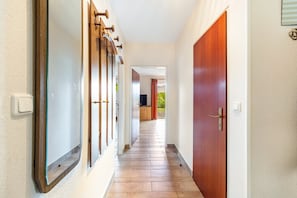 A hallway with a wooden door, a mirror, and a light switch on the wall. - Holiday Apartment for 5 People (80 m²) in Dahme (Dahme)