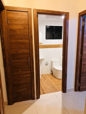 Eine Holztür zu einem Badezimmer mit Toilette, Waschbecken und einem angebrachten Spiegel.