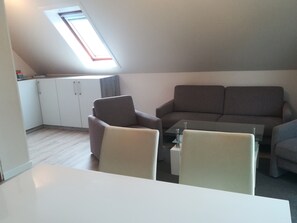 Un espace de vie de style loft avec une lucarne, un canapé, des fauteuils et une petite table.