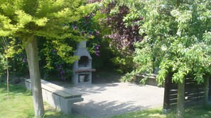 Un jardin agrĂ©mentĂ© dâun banc en pierre, dâune petite construction en pierre et dâune vĂ©gĂ©tation luxuriante.