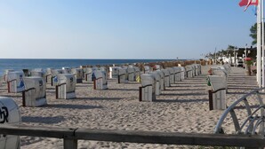Een strand met rijen witte strandhutten met nummers erop.