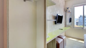 A room with a television mounted on the wall, a window with a view of buildings, and a small seating area with a bench and a table. - Stylish DBL Suite Escape W/ Free Wifi and Parking (Jakarta)