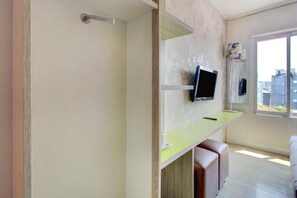 A room with a television mounted on the wall, a window with a view of buildings, and a small seating area with a bench and a table. - Stylish DBL Suite Escape W/ Free Wifi and Parking (Jakarta)