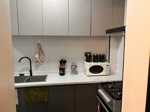 Ett kök med diskho, spis, mikrovågsugn och köksredskap.