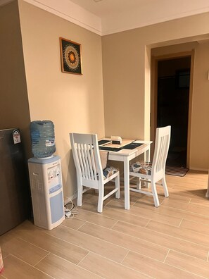 En matplats med ett bord och två stolar, en vattenautomat och en dekorativ väggdekoration.
