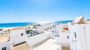 A coastal residential area with white buildings, a clear blue sky, and a beach in the background. - CREA Conil Apartments III (Conil de la Frontera)