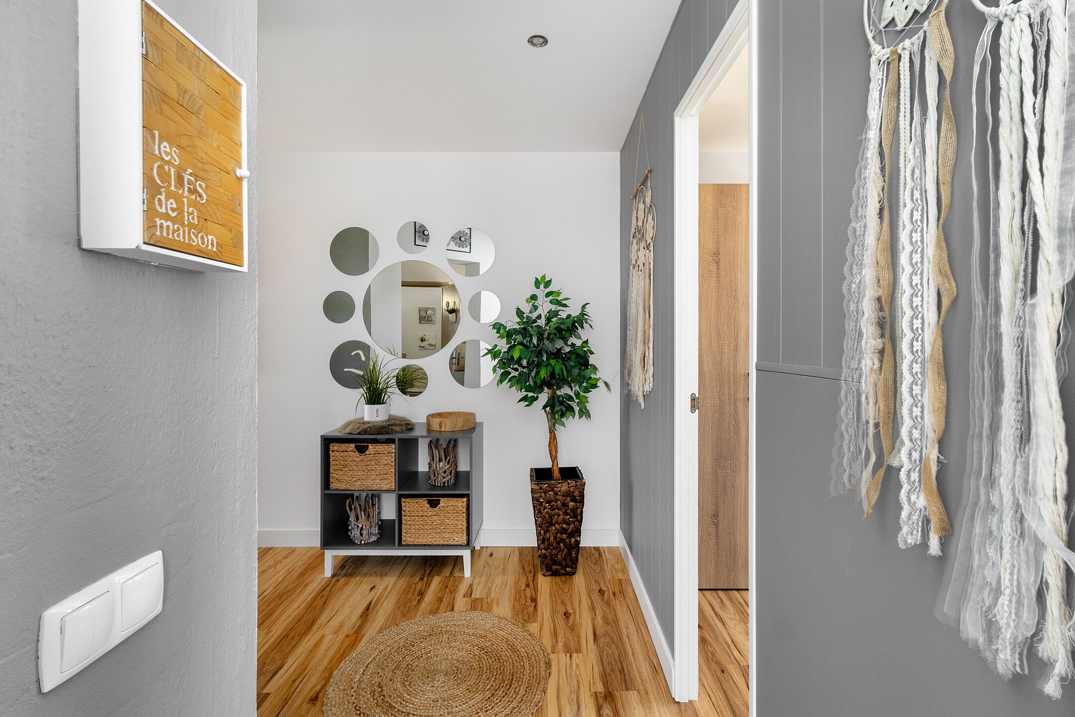 Un couloir doté d’un plancher en bois, d’une plante en pot, d’un miroir fixé au mur et d’un élément décoratif mural.