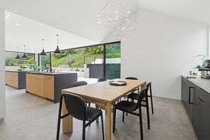 Eine moderne Küche mit Essbereich, großen Fenstern und Blick auf Grünflächen.
