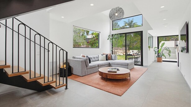 A modern interior with a staircase, a grey sectional sofa, a round coffee table, and large windows. - Modern Encinitas Retreat (Encinitas)