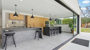 A modern kitchen with a bar area, wooden cabinets, and pendant lighting. - Modern Encinitas Retreat (Encinitas)