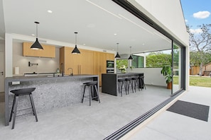 Eine moderne Küche mit Bar, Holzschränken und Pendelleuchten.