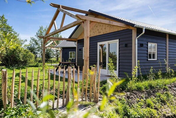 A house with a wooden deck, a picnic table, and a fenced garden.