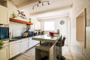 Una cocina moderna con armarios blancos, una isla de vidrio y un reloj en la pared.