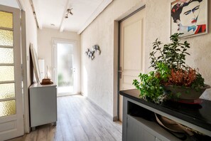 Un pasillo con una puerta, una planta en maceta y un cuadro colgado en la pared.