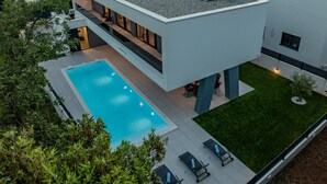 Ein modernes, zweistöckiges Haus mit Swimmingpool, Außenbereich und gepflegtem Rasen.
