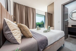 A modern hotel room with a large bed, a view through the window, and a bathroom with a mirror. - Villa Salt2 Zadarvillas (Nin)