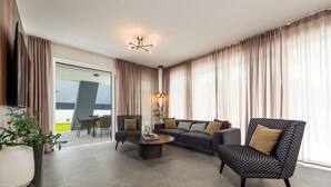 Ein modernes Wohnzimmer mit einer Couch, zwei Sesseln, einem Couchtisch und einem Fernseher.