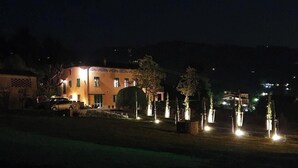 A building with a well-lit entrance and a parked car in front. - Cypress House (Pescia)