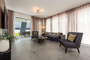 Ein modernes Wohnzimmer mit einer Couch, zwei Sesseln, einem Couchtisch und einem Fernseher.