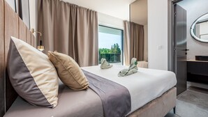 Una habitación de hotel moderna con una cama grande, vistas por la ventana y un baño con espejo.