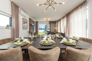 Ein Essbereich mit einem langen Tisch, gedeckt für eine Mahlzeit, einer Kandelaber und Blick ins Freie.